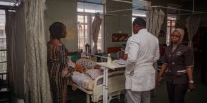 Professor Nike Bello examines a pregnant patient in a hospital bed.